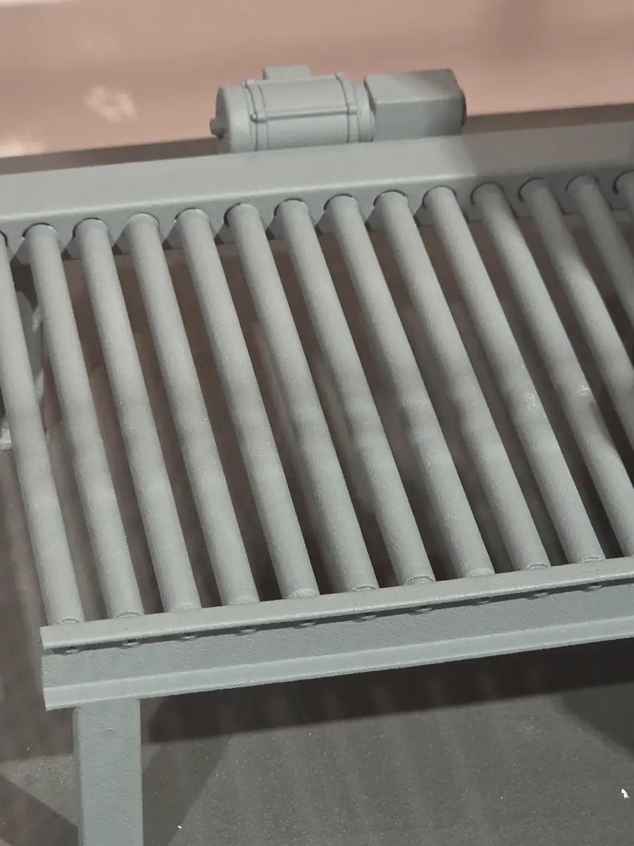 Close-up reference photograph of a primed 3D-printed roller conveyor and motor detail.